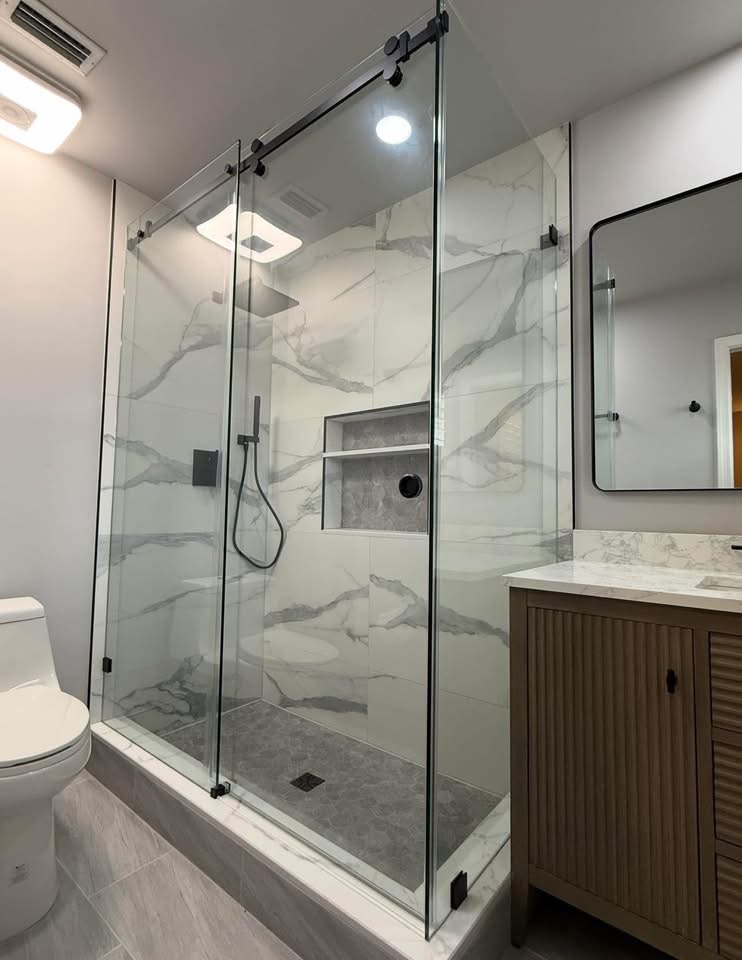 Frameless glass shower with book-matched marble and fluted vanity