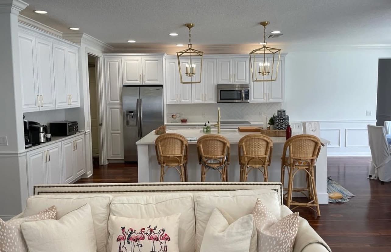 White kitchen with brass lantern pendants and rattan barstools